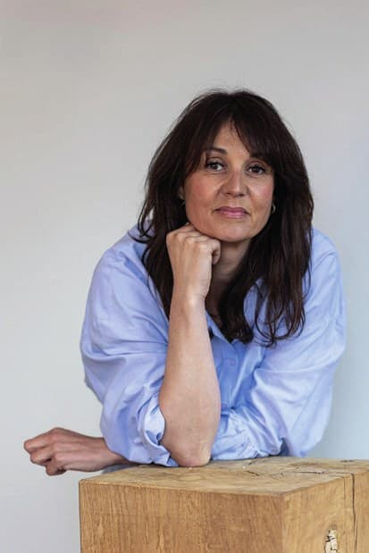 Marine Bouzidi Delayen, accoudée à un bloc de bois brut, chemise bleu ciel